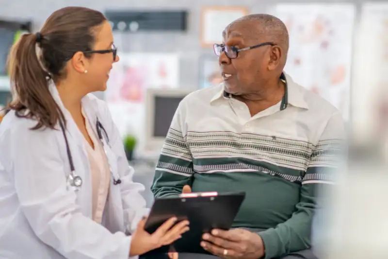 Close-up of a medical professional speaking with a patient about patient visits.